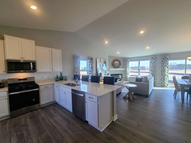 kitchen with backsplash, kitchen peninsula, sink, appliances with stainless steel finishes, and white cabinetry