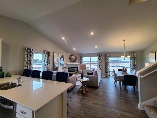 kitchen featuring dishwasher, lofted ceiling, sink, dark hardwood / wood-style floors, and decorative light fixtures