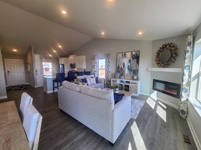 living room featuring plenty of natural light, dark hardwood / wood-style floors, and vaulted ceiling