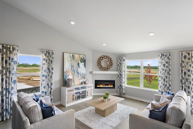 living room with light wood-type flooring, a wealth of natural light, and vaulted ceiling