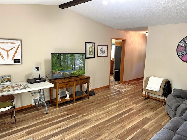 living room featuring hardwood / wood-style floors, lofted ceiling with beams, and a textured ceiling