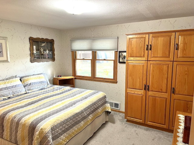 bedroom with light carpet and a textured ceiling