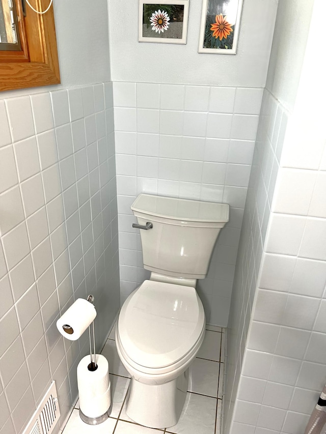 bathroom featuring tile patterned flooring, toilet, and tile walls