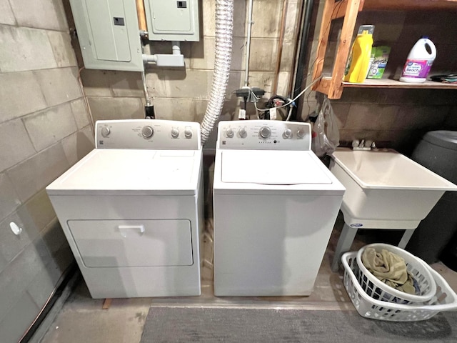 clothes washing area with separate washer and dryer, electric panel, and sink