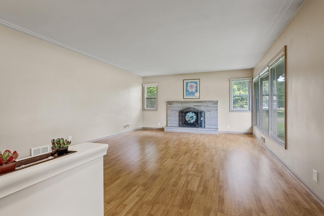 unfurnished living room featuring plenty of natural light, light hardwood / wood-style floors, and a brick fireplace