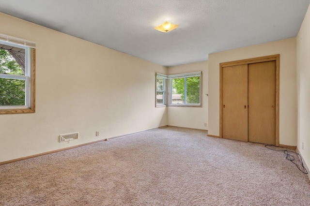 unfurnished bedroom with carpet floors, a textured ceiling, and a closet