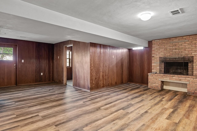 unfurnished living room featuring a textured ceiling, wood walls, and a fireplace