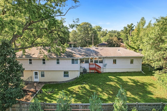 rear view of property with central AC and a lawn