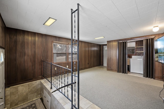 interior space featuring wood walls, washer / dryer, and light carpet