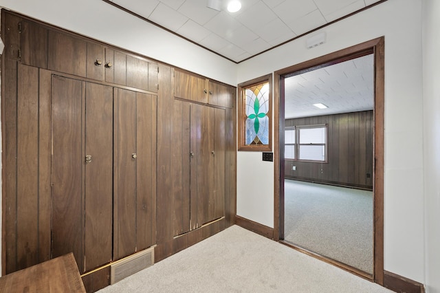 unfurnished bedroom with light colored carpet, a closet, and wood walls