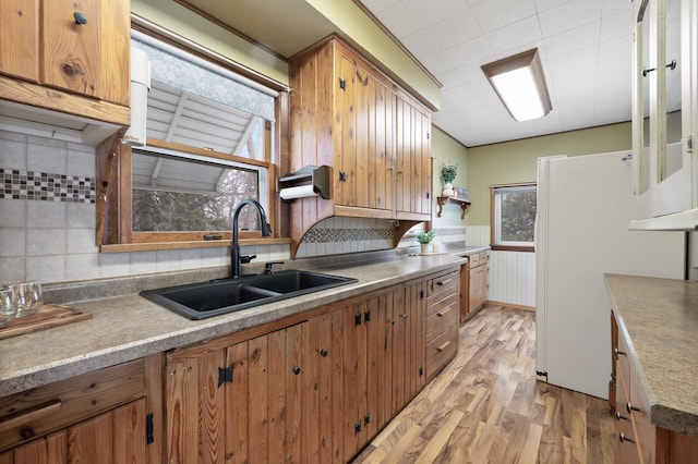 kitchen with decorative backsplash, white refrigerator, light wood-type flooring, and sink