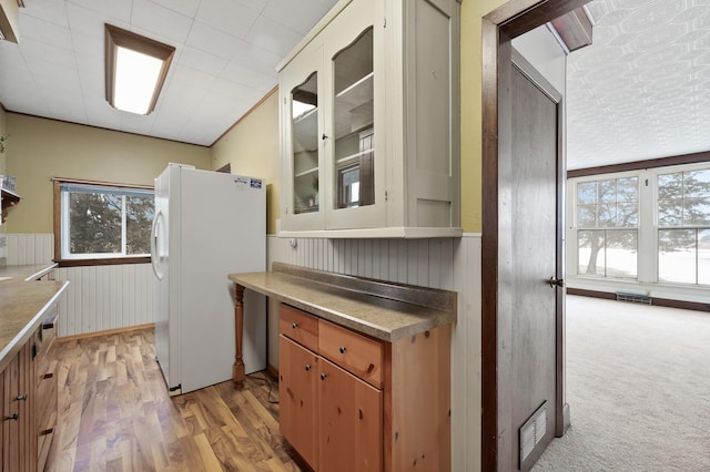 kitchen with white fridge, light hardwood / wood-style floors, and wooden walls