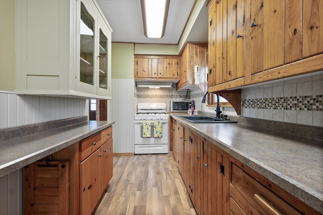 kitchen with backsplash, sink, white gas range oven, and light hardwood / wood-style flooring