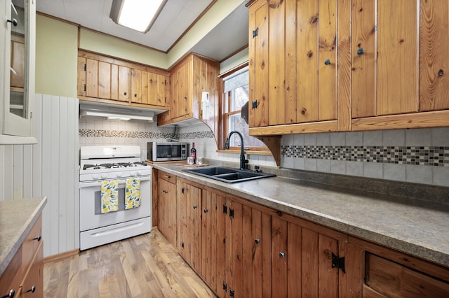 kitchen featuring sink, light hardwood / wood-style flooring, ornamental molding, tasteful backsplash, and white range with gas stovetop