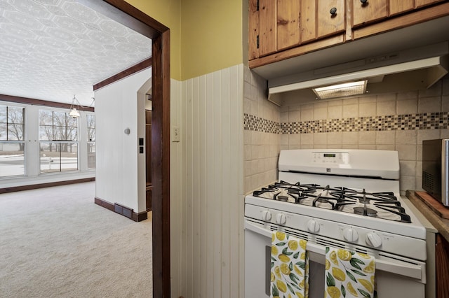 kitchen featuring white range with gas stovetop, a textured ceiling, and light colored carpet