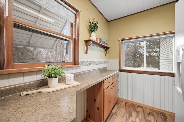 kitchen with lofted ceiling, light wood-type flooring, and crown molding