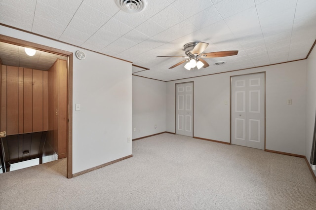 interior space with ceiling fan, crown molding, and light carpet