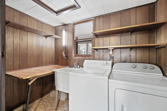 laundry area with sink, wooden walls, and washing machine and clothes dryer