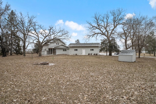 back of property featuring a fire pit and a storage shed