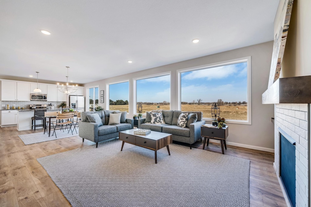 living room with a wealth of natural light, light hardwood / wood-style flooring, and an inviting chandelier