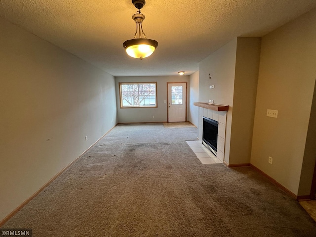 unfurnished living room featuring a tiled fireplace, light carpet, and a textured ceiling