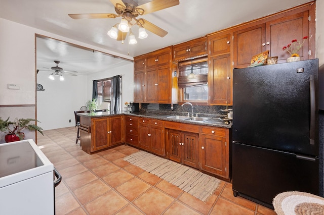 kitchen featuring decorative backsplash, light tile patterned flooring, black fridge, and sink