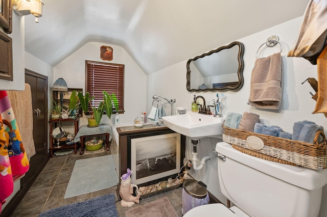 bathroom with toilet, sink, and vaulted ceiling