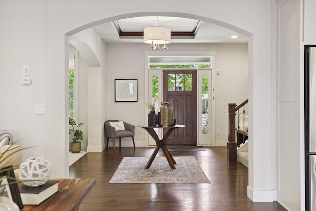 foyer entrance with crown molding, dark wood-type flooring, and a tray ceiling