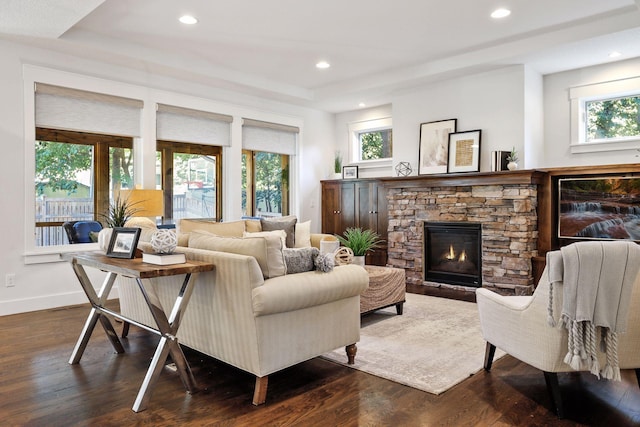 living room with dark wood-type flooring and a stone fireplace