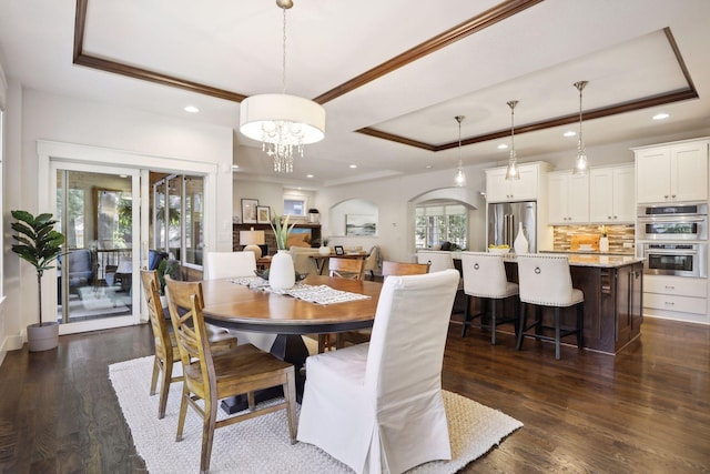 dining area with a raised ceiling, ornamental molding, a healthy amount of sunlight, and dark hardwood / wood-style floors