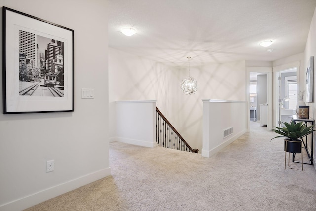 hall with carpet flooring, a chandelier, and a textured ceiling