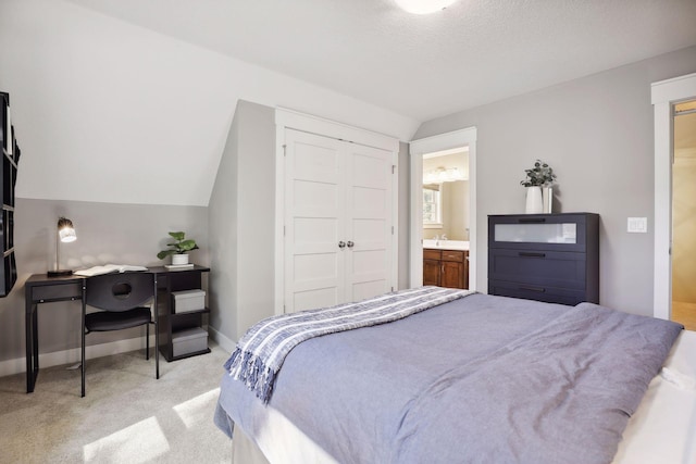 bedroom featuring sink, vaulted ceiling, a textured ceiling, a closet, and light colored carpet