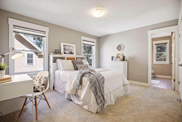 bedroom with multiple windows, ensuite bathroom, and light carpet