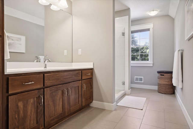 bathroom with vanity, tile patterned flooring, lofted ceiling, and a shower