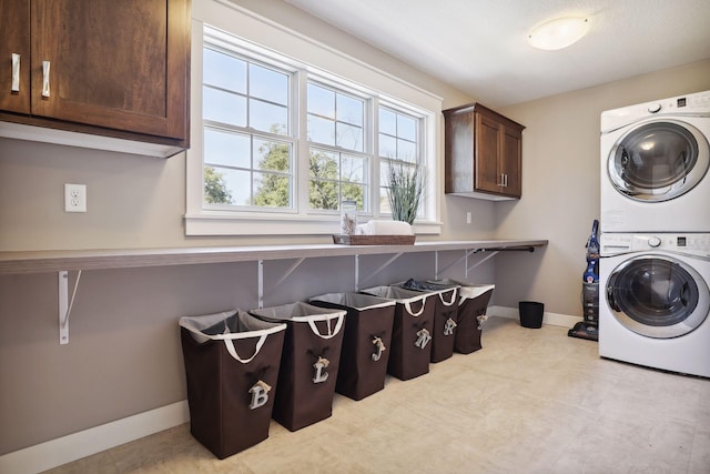 clothes washing area with cabinets and stacked washer and dryer