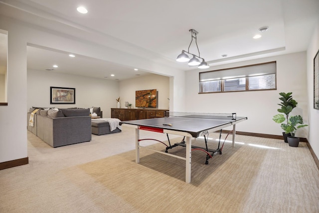 game room featuring a tray ceiling and light carpet