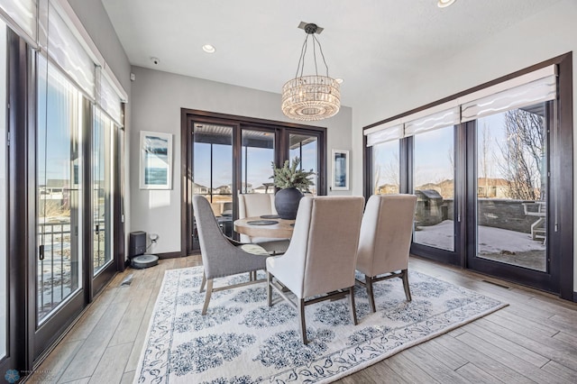 dining space featuring light wood-type flooring, an inviting chandelier, and a healthy amount of sunlight