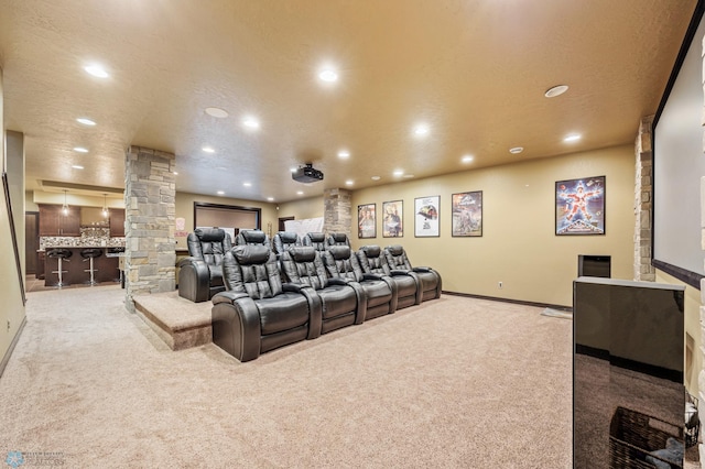 carpeted home theater featuring ornate columns and a textured ceiling