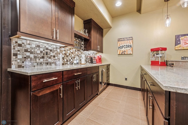 kitchen with light stone countertops, tasteful backsplash, sink, decorative light fixtures, and light tile patterned flooring