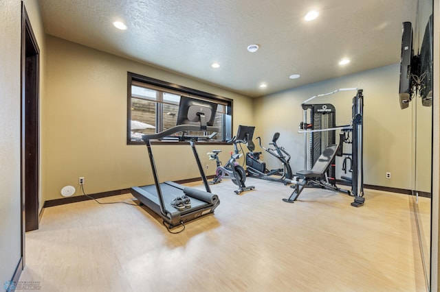 workout area featuring a textured ceiling and light hardwood / wood-style floors