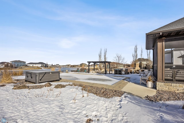 snowy yard featuring a pergola and a hot tub