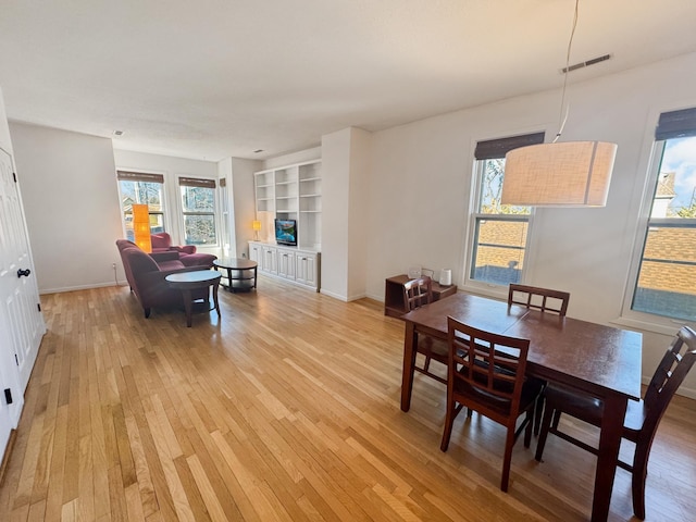 dining area with built in shelves and light hardwood / wood-style floors