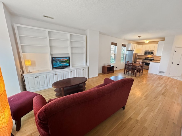 living room with a textured ceiling and light wood-type flooring