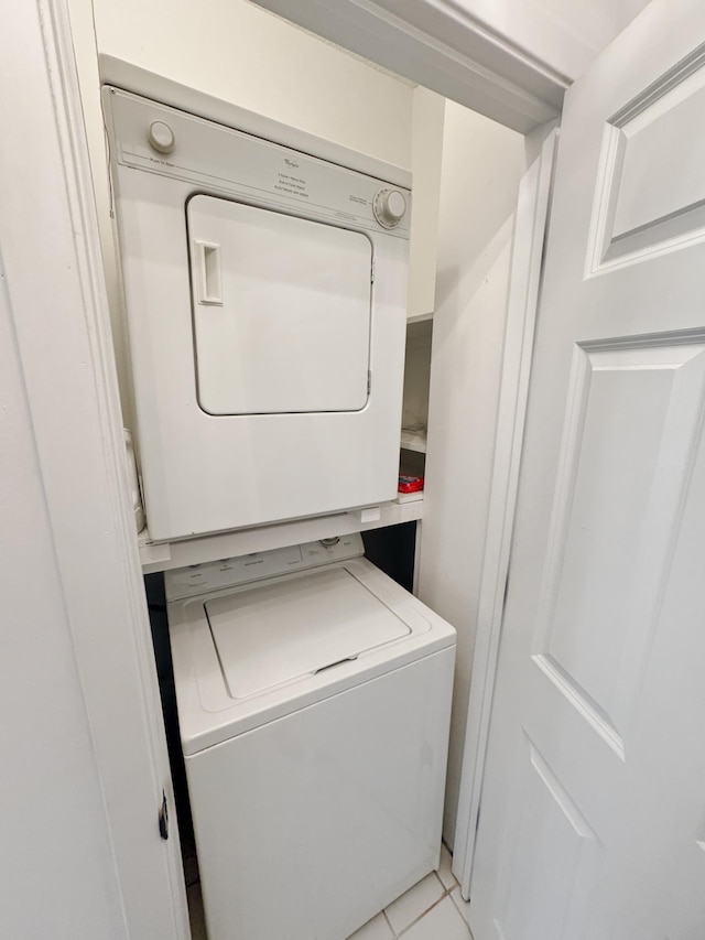 washroom with stacked washing maching and dryer and light tile patterned floors