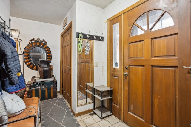 entryway with a textured ceiling and light tile patterned floors