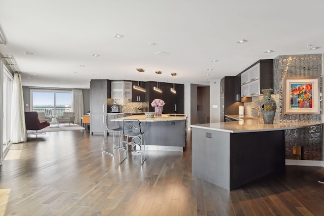 kitchen featuring dark wood-type flooring, a kitchen breakfast bar, backsplash, kitchen peninsula, and pendant lighting