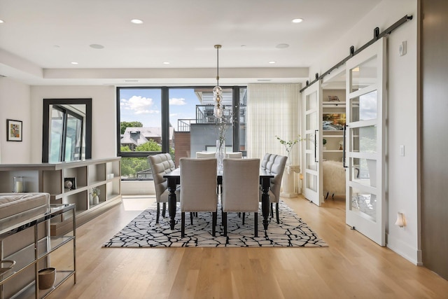 dining space featuring an inviting chandelier, light hardwood / wood-style flooring, and a barn door