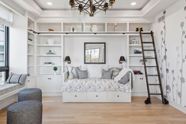 bedroom featuring an inviting chandelier, crown molding, and light hardwood / wood-style floors