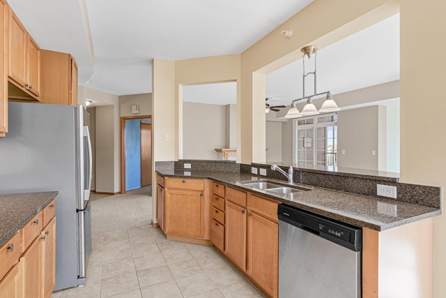 kitchen featuring dark stone counters, hanging light fixtures, sink, ceiling fan, and appliances with stainless steel finishes