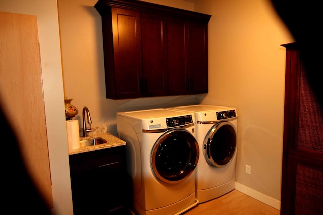 clothes washing area with cabinets, washer and dryer, and sink